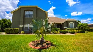 Een tweelaags huis met een verzorgd gazon en een palmbom in de voortuin.