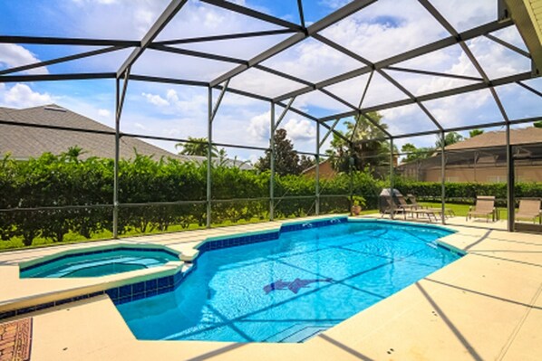 Relax by the pool surrounded by lounge chairs and a barbecue grill.