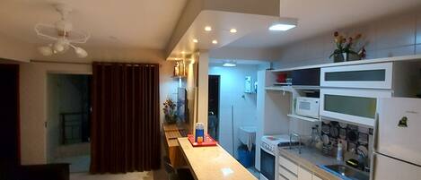 Una cocina moderna con una isla central, armarios blancos y un microondas.
