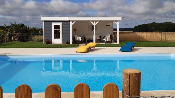 A poolside area with a covered patio, a lounge chair, and a small deck. - Private pool in a beautiful, romantic retreat, offering peace and quiet (Noyant-Villages)