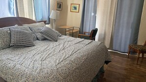 Un dormitorio con una cama grande, un escritorio, una silla y cortinas.
