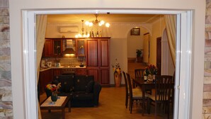 Una sala de estar con sofá, mesa de centro y sillas, un comedor con mesa y sillas, y una cocina con armarios y electrodomésticos.