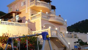 Una casa grande de varios pisos con balcón, escaleras y zona de piscina.