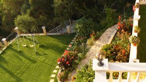 Un jardín bien cuidado con césped, parterres de flores y una valla blanca.