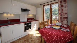 Una cocina con armarios blancos, encimera roja y un comedor con mantel rojo.