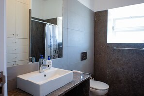 Ein modernes Badezimmer mit Waschbecken, Spiegel, Duschvorhang und Toilette.