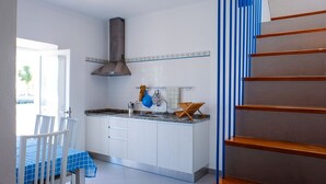 Une cuisine moderne avec des meubles blancs, une hotte de cuisinière en acier inoxydable et un escalier à rayures bleues.