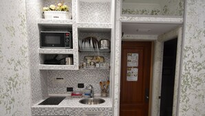 A compact kitchen with a microwave, sink, and small refrigerator. - Room Vichy (Roma)