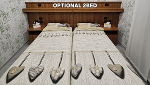 A room with an optional 2-bed setup, featuring two beds with matching headboards and a central nightstand. - Room Vichy (Roma)