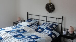 A bed with a blue and white patterned bedspread, two bedside tables with lamps, and a wall-mounted light fixture. - Family-friendly spacious and luxurious detached vacation home for 8 to 9 people (Lenterode)
