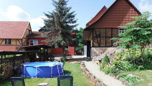 A residential area with a blue inflatable pool, two lawn chairs, and a stone wall. - Family-friendly spacious and luxurious detached vacation home for 8 to 9 people (Lenterode)