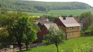 A rural village with traditional houses, a fenced area, and a green valley in the background. - Family-friendly spacious and luxurious detached vacation home for 8 to 9 people (Lenterode)