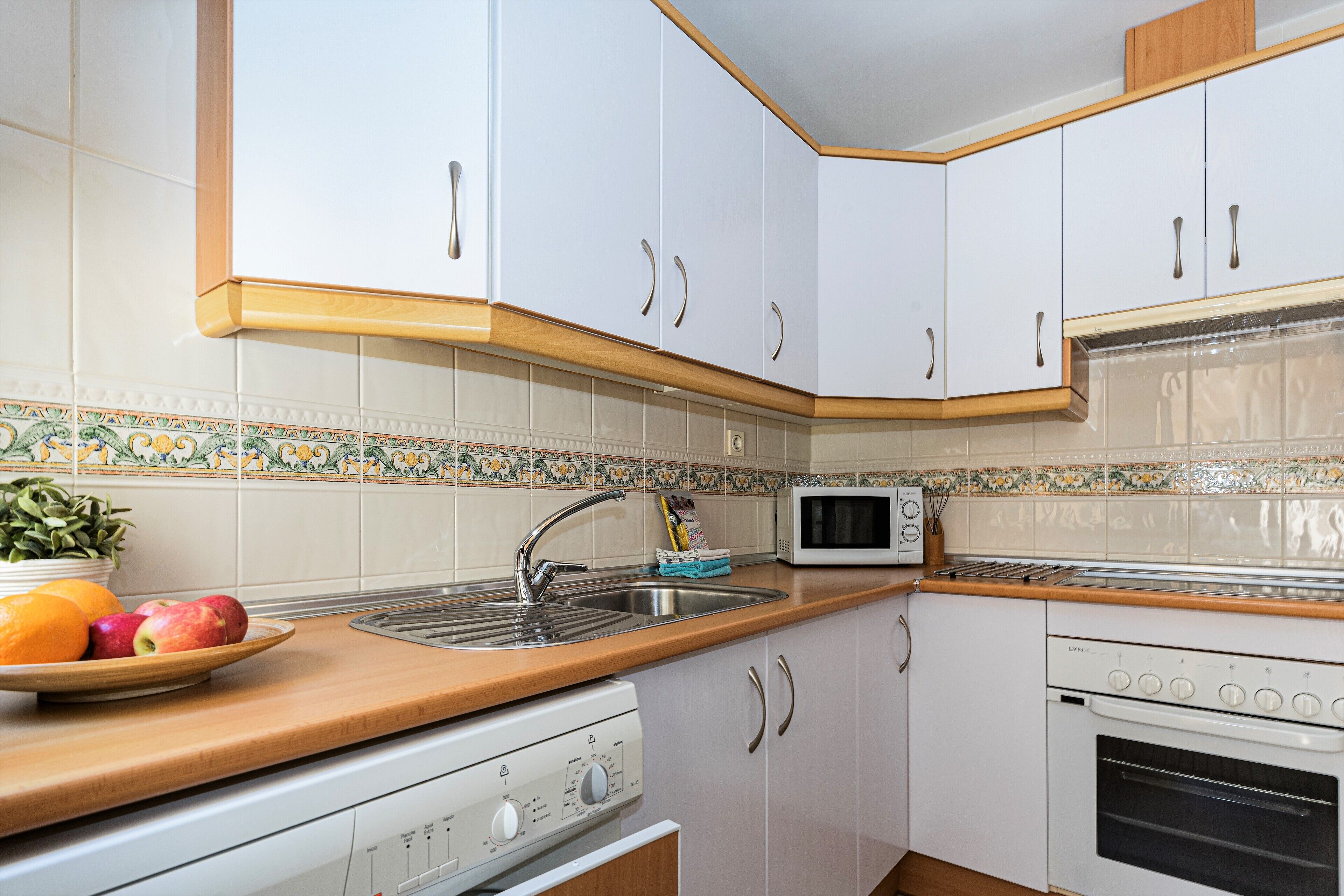 A kitchen with white cabinets, a microwave, a stove, and a sink.