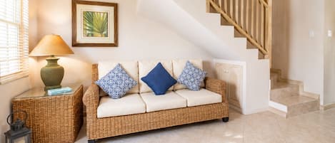 Un salon avec un canapé, une lampe, une lanterne et un escalier.