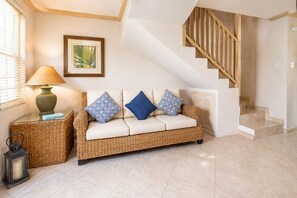A living room with a sofa, a lamp, a lantern, and a staircase.
