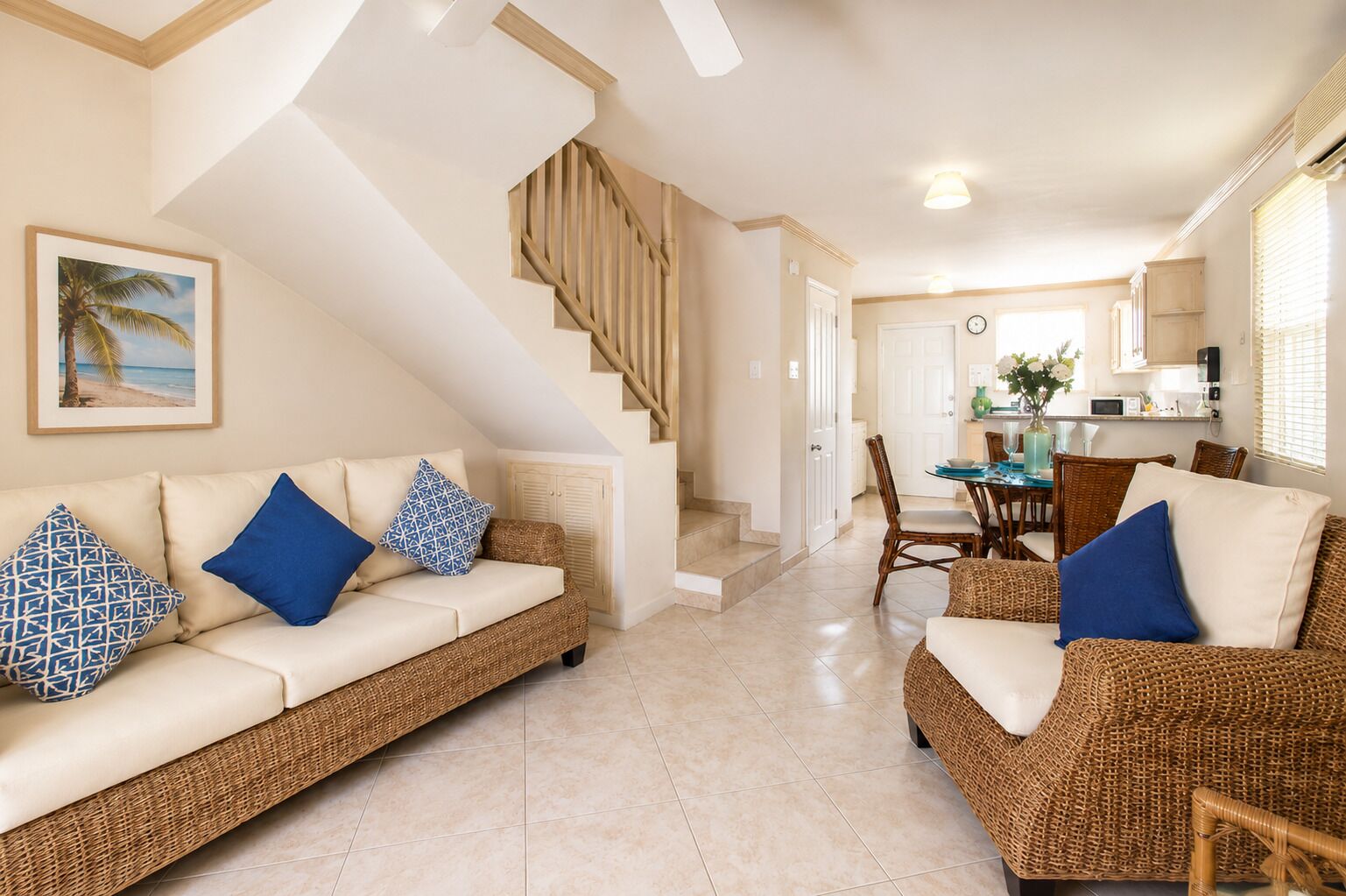 A living room with a sofa, two chairs, a staircase, and a dining area with a table and chairs.