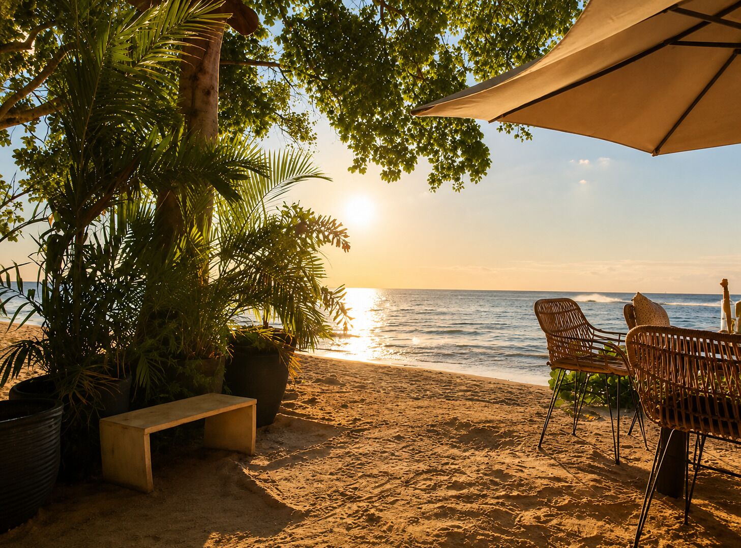 A beach setting with a bench, chairs, and a large umbrella providing shade.