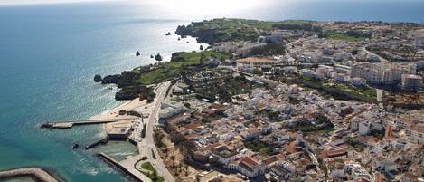 Vista aérea de uma cidade costeira com edifícios residenciais, uma igreja branca imponente e uma área de praia.