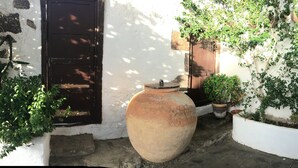 A narrow courtyard with a white wall featuring a stone pattern, a large pot, and several potted plants. - 5 ***** Serena Studio with private chill out. (Arrecife)