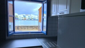 A kitchen with a window overlooking a beach and buildings. - 5 ***** Serena Studio with private chill out. (Arrecife)
