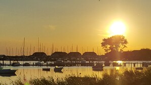 Ein Sonnenuntergang über einem Yachthafen mit Booten und einer Mole.