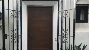 A brown wooden door with a decorative metal gate, white walls, and a tiled arch above the door.