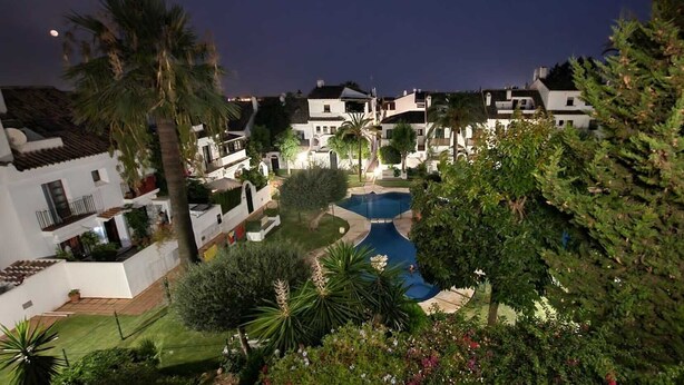 A residential area with houses, a swimming pool, and lush greenery.