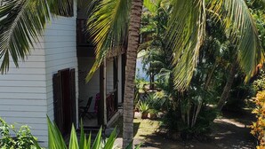 Uma escadaria leva a um edifício branco, rodeado por vegetação tropical.