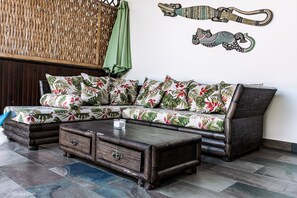 A room with a sectional sofa, a wooden coffee table, and a woven partition. - Large villa **** beachfront with pool (La Saline-Les-Bains)