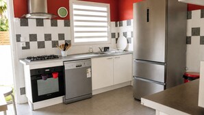 A modern kitchen with a gas stove, dishwasher, oven, and a stainless steel refrigerator. - Large villa **** beachfront with pool  (La Saline-Les-Bains)
