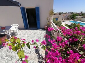 A terrace with a patterned floor, a white chair, a table, and a potted plant. - Charming house Mezraya Djerba S + 1 (Djerba)