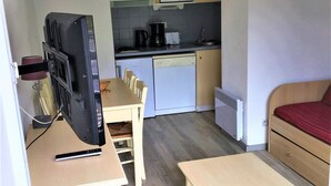 Eine kompakte Küchenzeile mit Mikrowelle, Kaffeemaschine und einer kleinen Essecke mit Tisch und Stühlen.