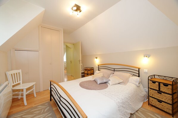 A bedroom with a bed, a chair, a bedside table, and a wardrobe.