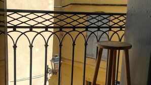 A balcony with a metal railing and a wooden stool.