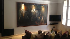 A living room with a large painting, a television, and a sofa with cushions.