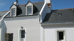 A white building with a sloped roof, a small dormer window, and a door with a window. - CHARMING LITTLE HOUSE Belliloise  (Sauzon)