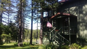 Une cabane avec une véranda, une terrasse en bois et une vue sur un lac.