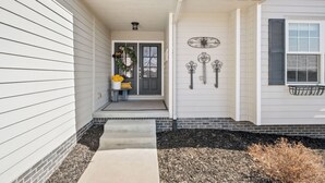 A house with a front porch, a wreath, and decorative wall art. - HUGE, 10 BEDS, FAMILIES, REUNIONS & RETREATS! LAKE FUN 1 MILE-FREE POOL PASSES! (Omaha)
