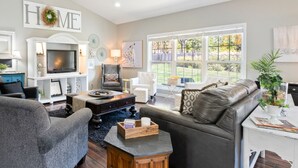 A living room with a fireplace, a television, and a large window with a view of the outdoors. - HUGE, 10 BEDS, FAMILIES, REUNIONS & RETREATS! LAKE FUN 1 MILE-FREE POOL PASSES! (Omaha)