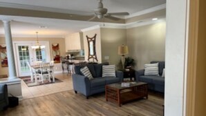 Ein geräumiges Wohnzimmer mit Holzboden, zwei Sofas, einem Couchtisch und einem Deckenventilator.