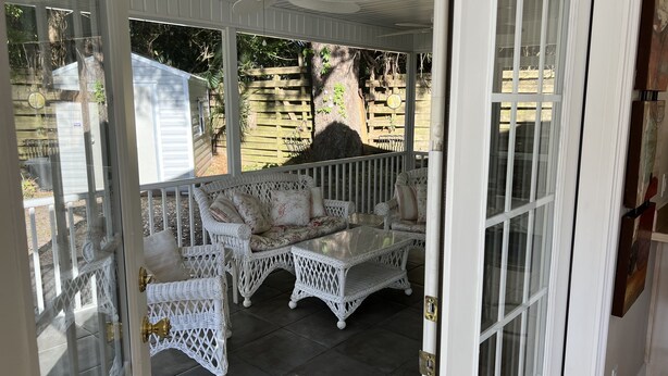 Eine überdachte Terrasse mit Korbmöbeln und einer Glastür zu einem Außenbereich.