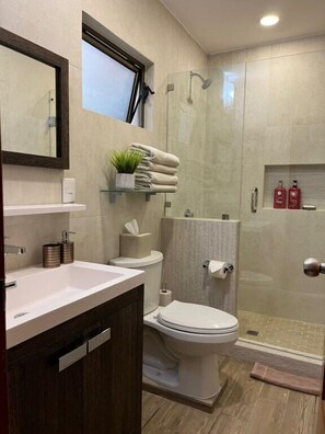 Un baño moderno con lavamanos, inodoro y zona de ducha.