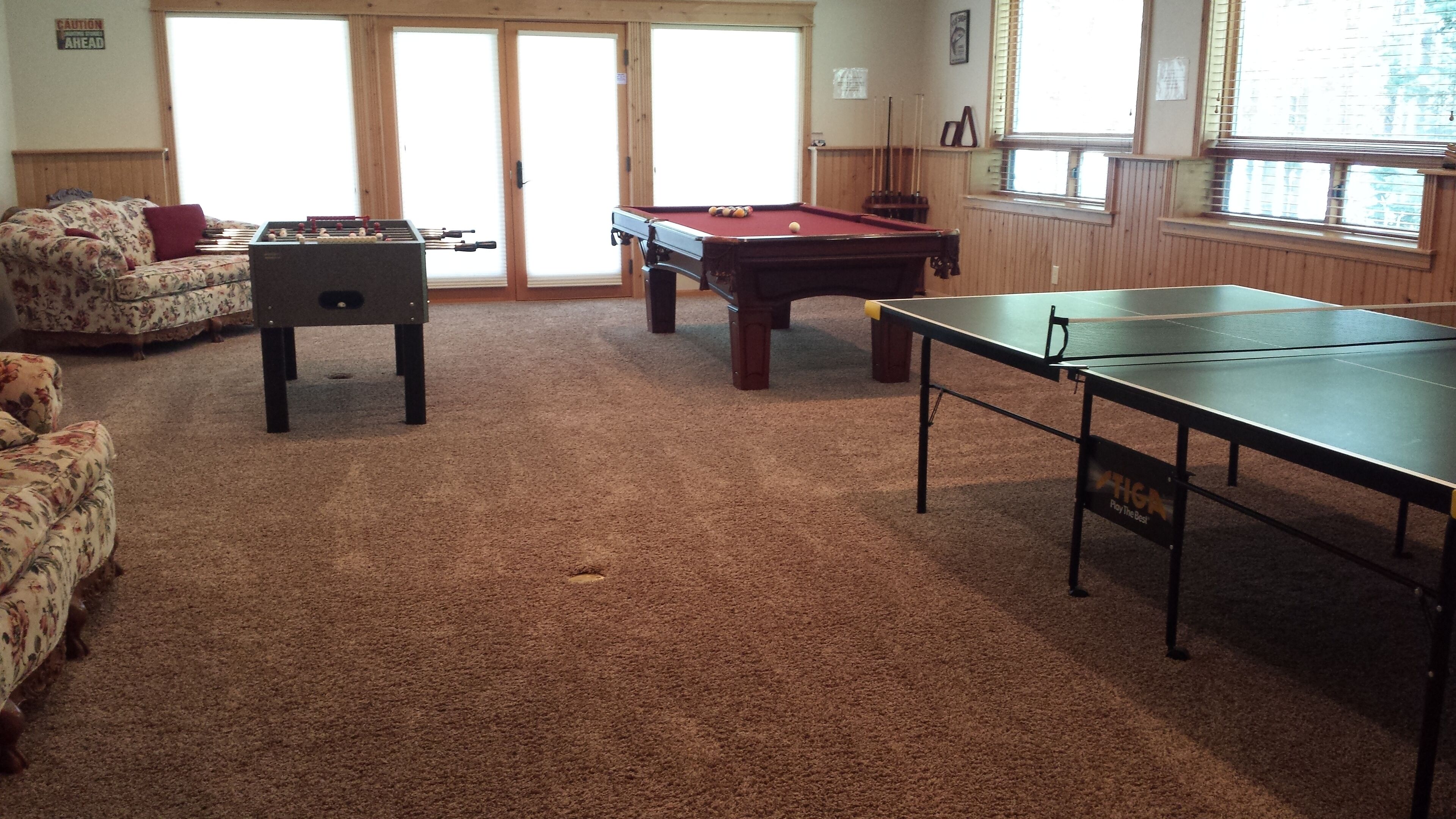 A room with a pool table, foosball table, and ping pong table.