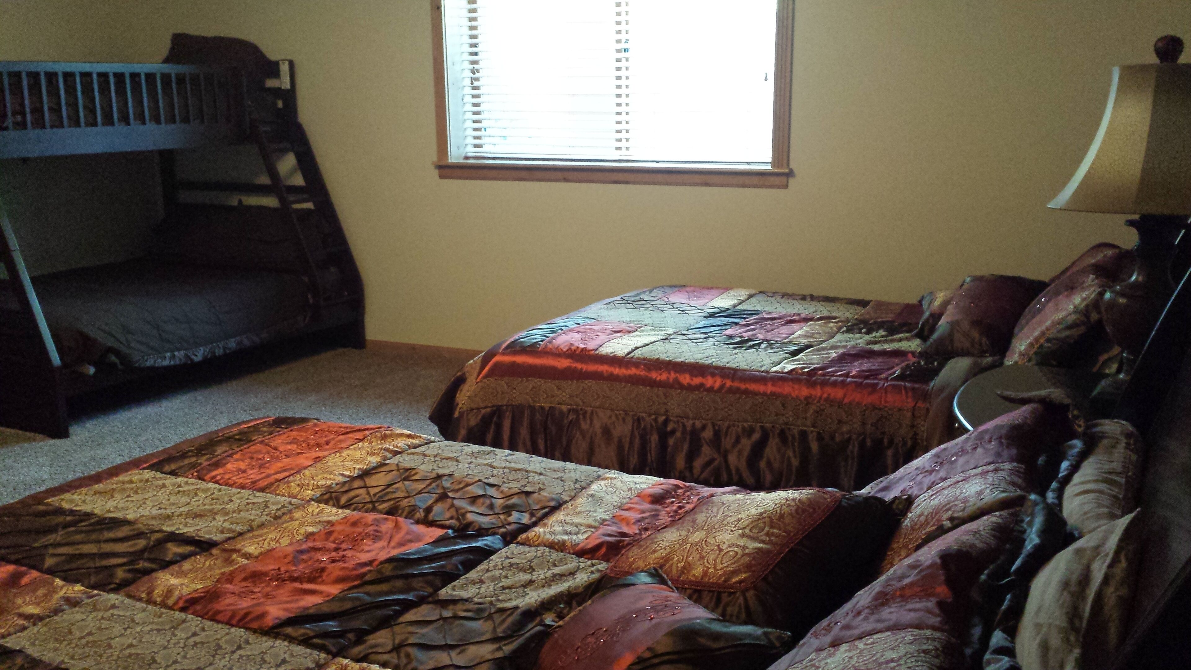 A bedroom with bunk beds and a bed with a patterned quilt.