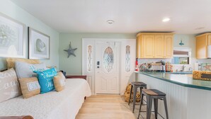 A cozy bedroom with a bed, a small sitting area, and a kitchen with wooden cabinets and a bar area. - Sandbars/Fishing/Boat Rental Dreamy Keys Gateway Home On The Water! (Tavernier)