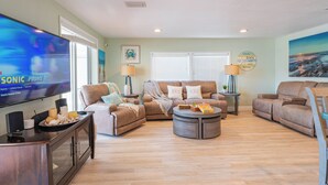 A spacious living room with a large flat-screen TV, a sectional sofa, a coffee table, and a wooden floor. - Sandbars/Fishing/Boat Rental Dreamy Keys Gateway Home On The Water! (Tavernier)
