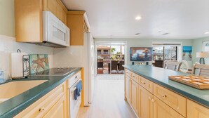 A kitchen with wooden cabinets, a microwave, and a green countertop. - Sandbars/Fishing/Boat Rental Dreamy Keys Gateway Home On The Water! (Tavernier)