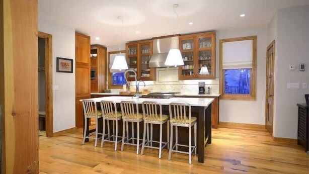 A kitchen with wooden cabinets, a central island with chairs, and pendant lighting.