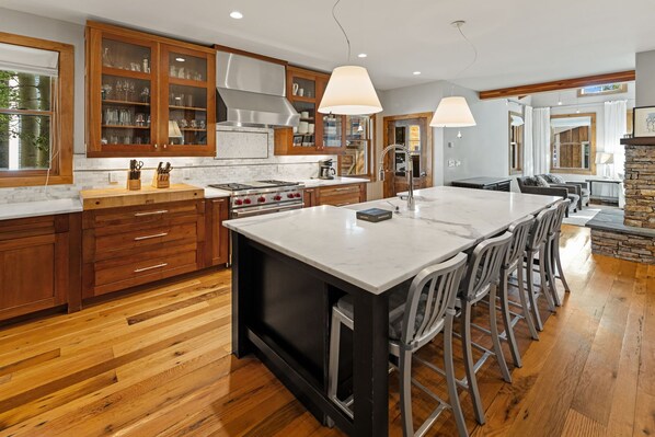A modern kitchen with wooden cabinets, a large island, and a dining area with bar stools.