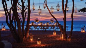 A beachside dining setup with tables and chairs, surrounded by trees and lanterns. - Splendid 5-bedroom ocean-view villa at The Four Seasons Punta Mita (Punta de Mita)